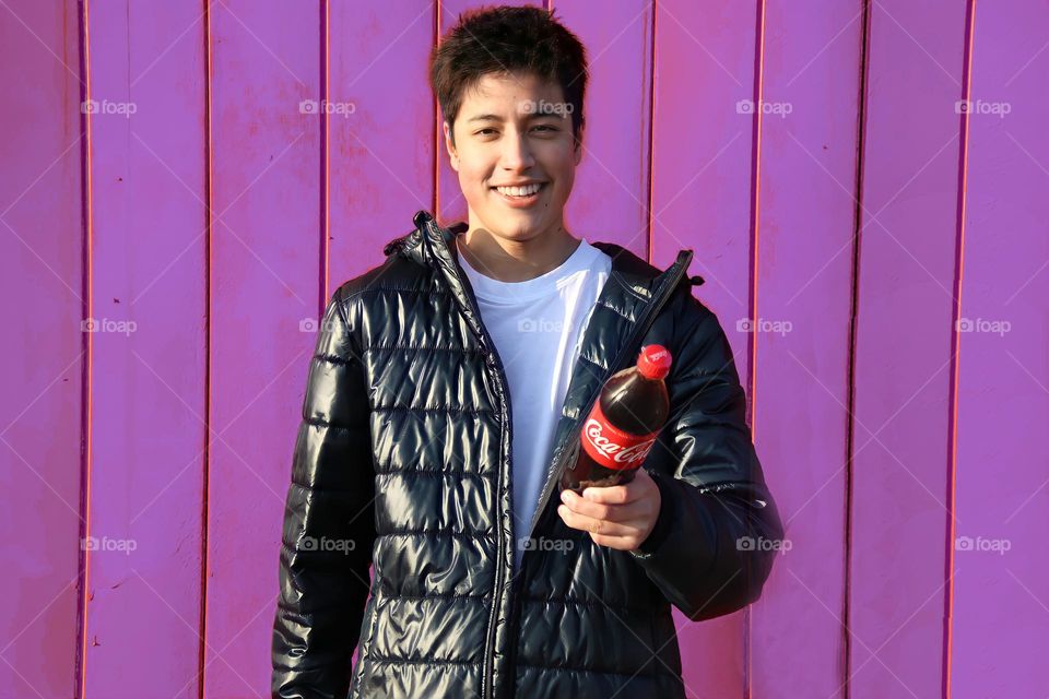 Handsome happy young man with a bottle of coca cola