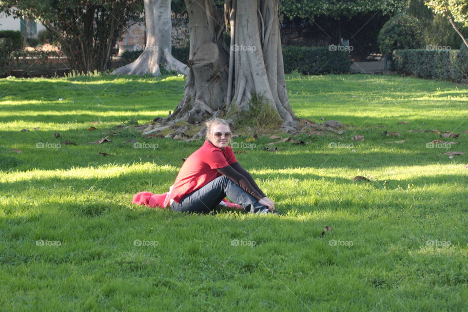 Beautiful young woman sitting on grass in park