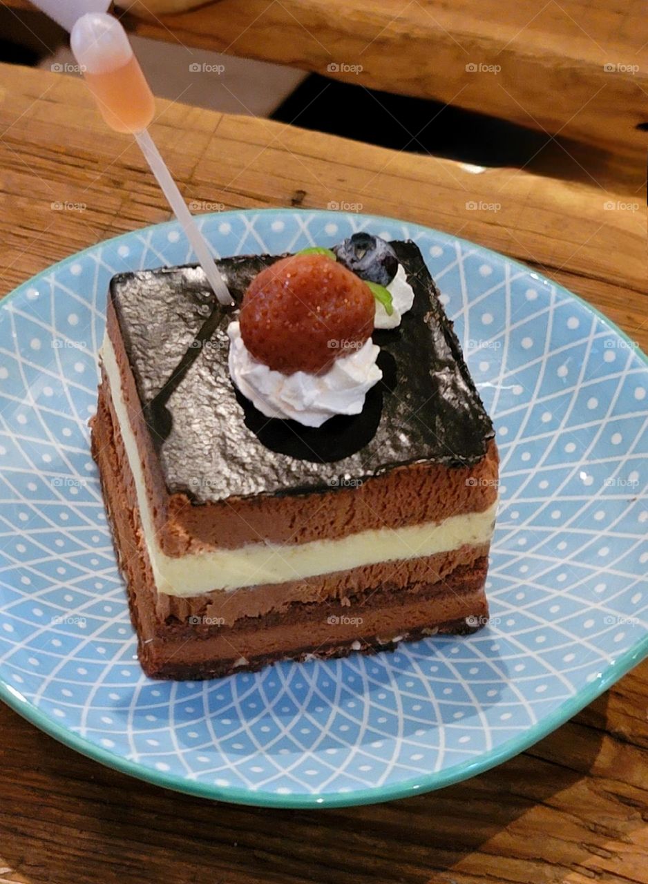 Chocolate cake with whipped cream, strawberries and blueberries paired with dropper wine