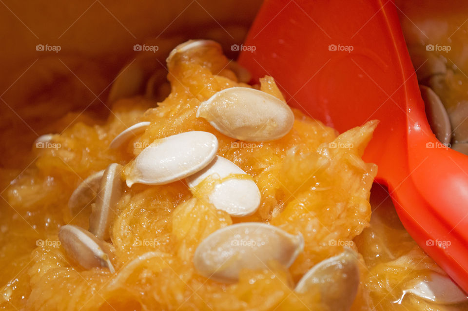 Pumpkin carving activity scooping pumpkin seeds and pulp out of fresh autumn harvest pumpkin to make jack o’lantern with pumpkin carving scoop tool 