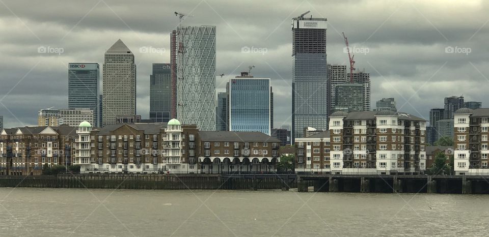 London, UK. Apartments on the Thames River with business towers behind 