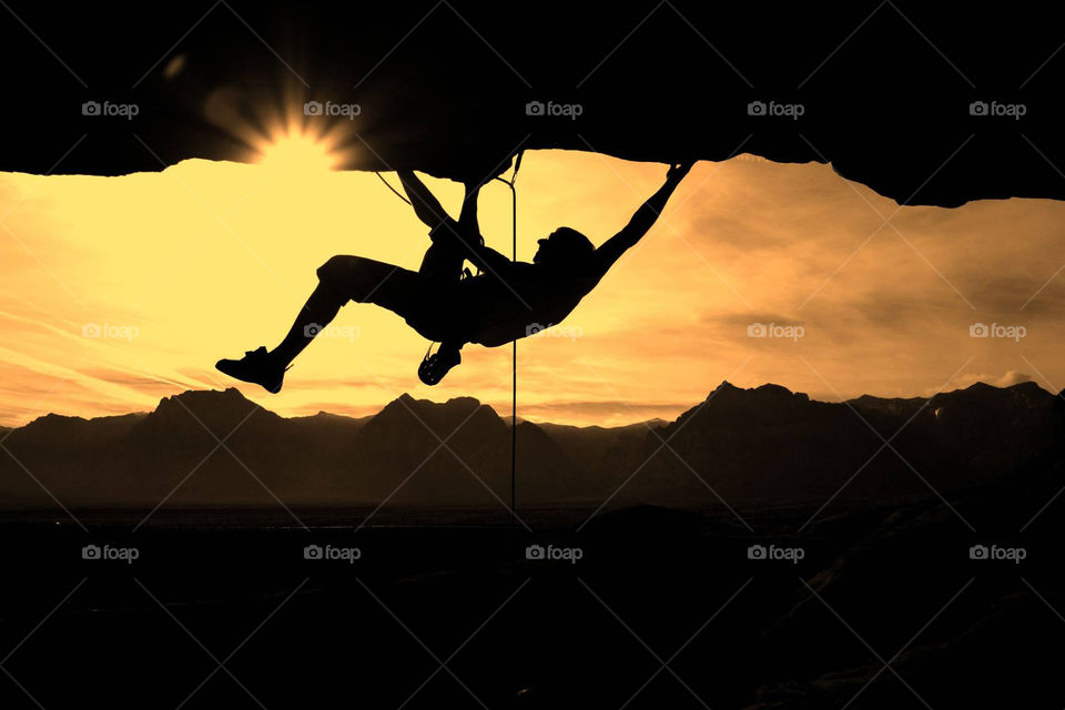 Silhouette of a person climbing on rock