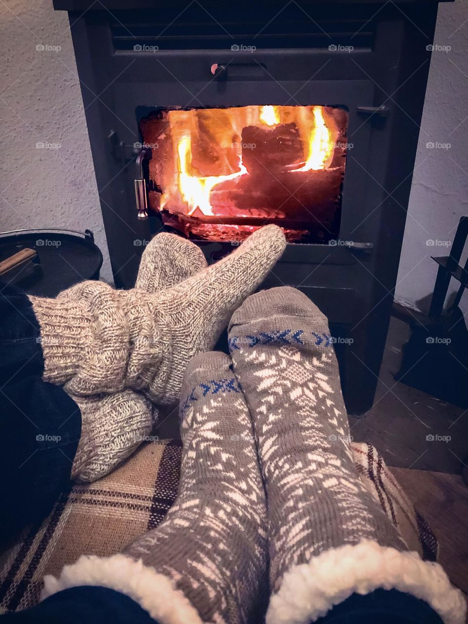 Two pairs of feet in winter socks with them up by the fire