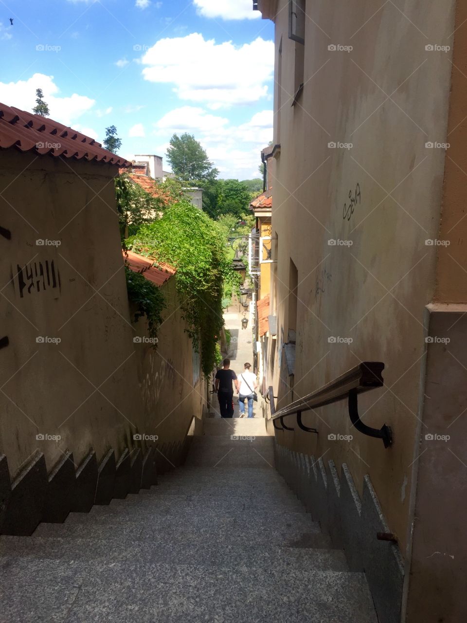 Two walking down a narrow street with staircase 