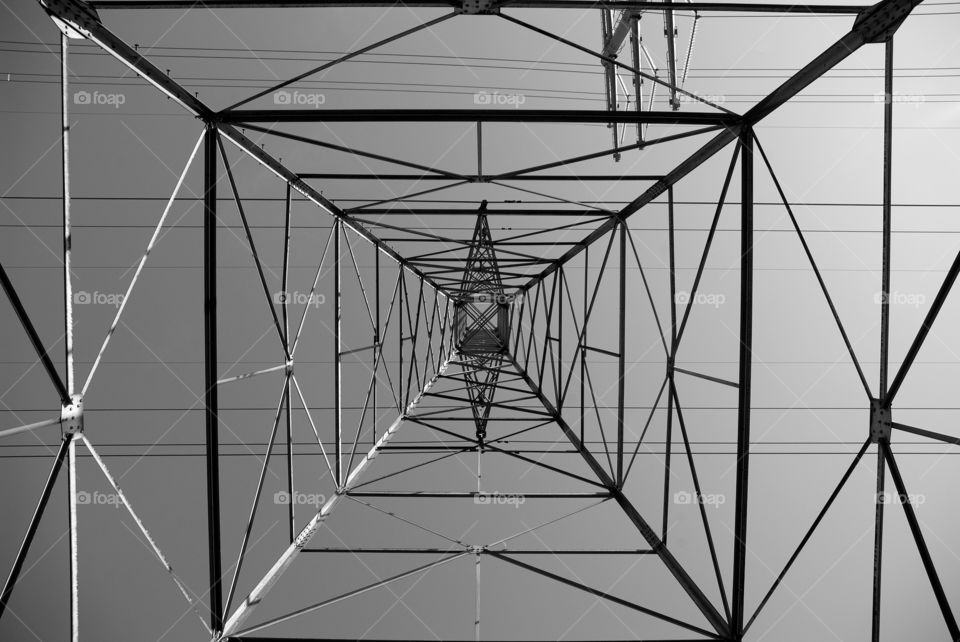 Black and white 90 degree true vertical angle of a steel high tension power tower.