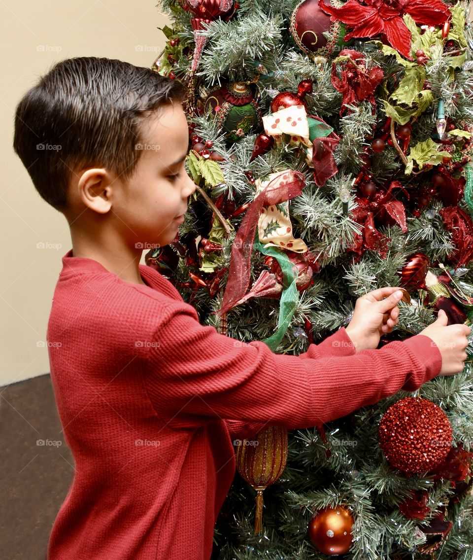 Young boy decorating the Christmas tree 