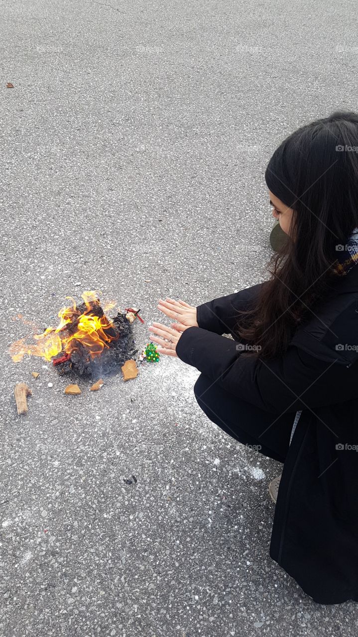 Warming hands by a burning gingerbread house