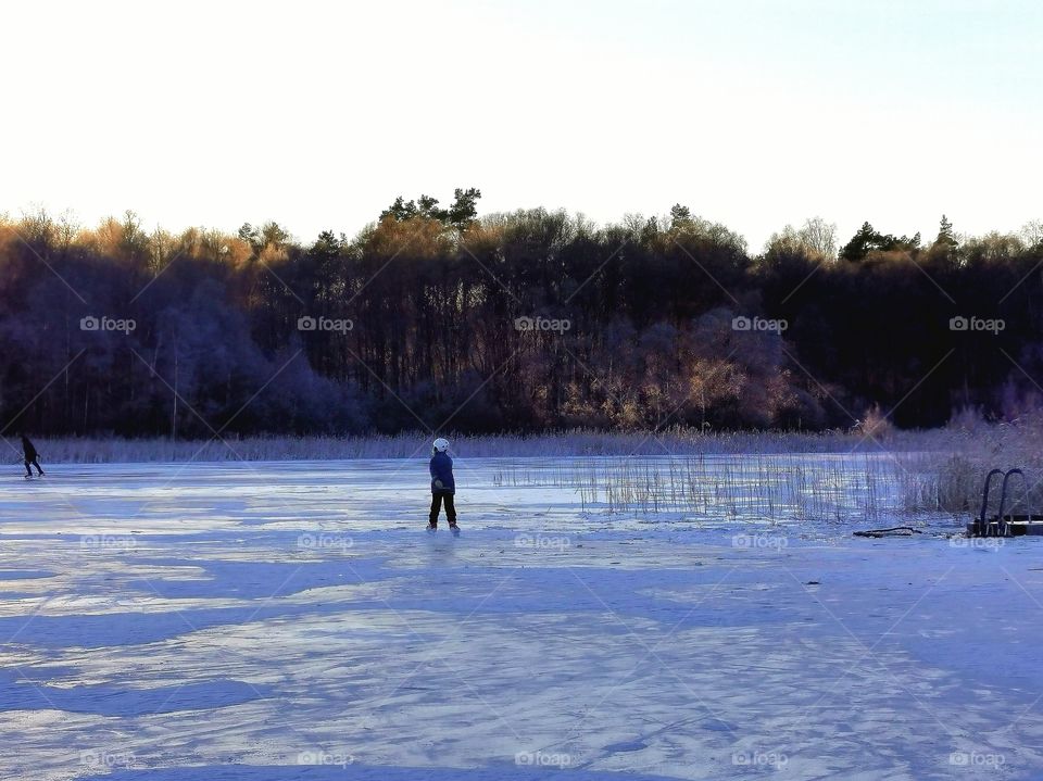 Child skating on the ice at sunset