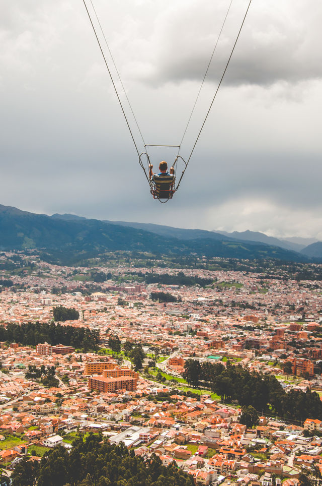 Man having fun on a swing over the city
