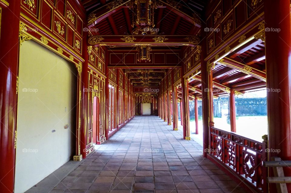 A passage for kings in old palaces , the pillars and things made of wood are painted red and a little yellow, the floor is lined with red brick now they are old and worn a lot , on the left are the doors