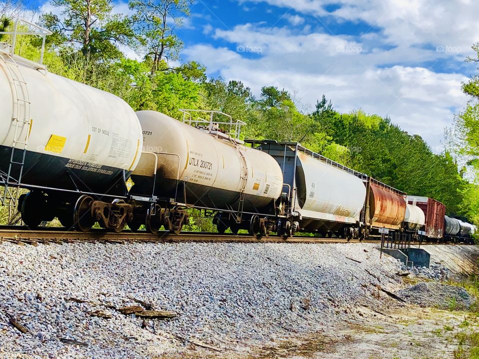 Train box and tanker cars on track in nature under the clouds 