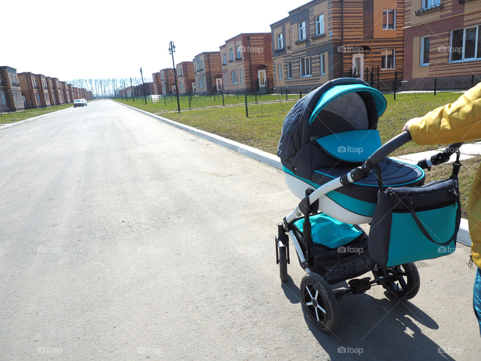 a woman with a blue gray stroller walking down the street cottage village.