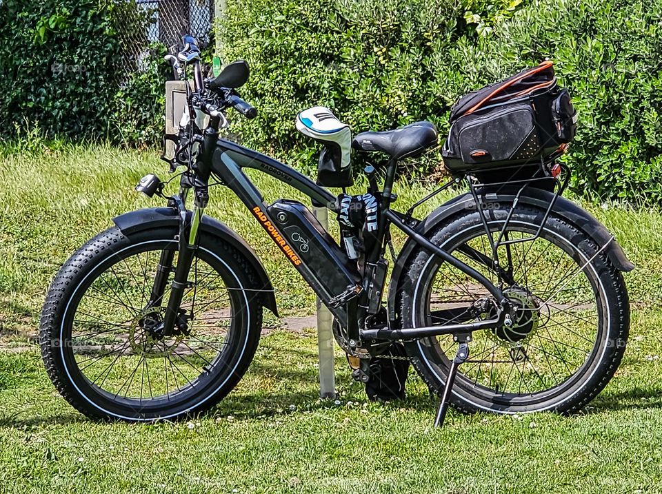 Black sports Bicycle parked in a park on a warm spring day with golf clubs ready for an adventure 