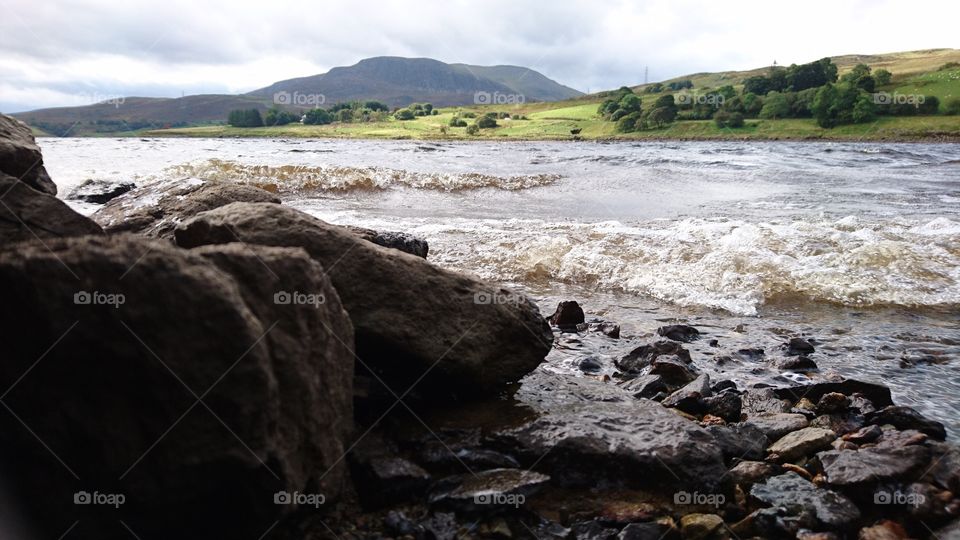 rocky open water with greenery and mountain background in Snowdonia national park Wales