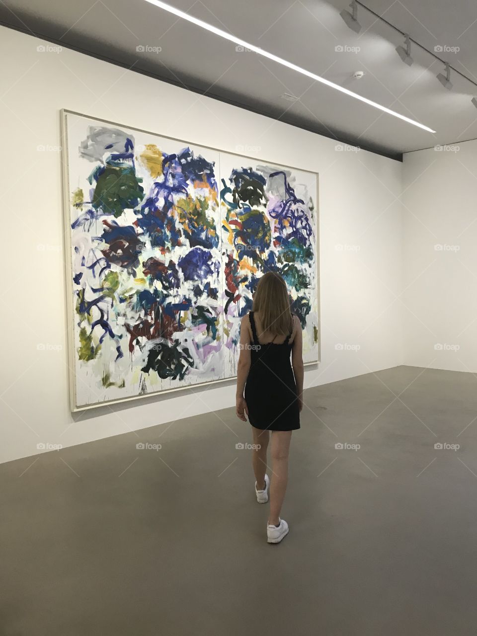 Girl in dress in the museum in front of a work of art