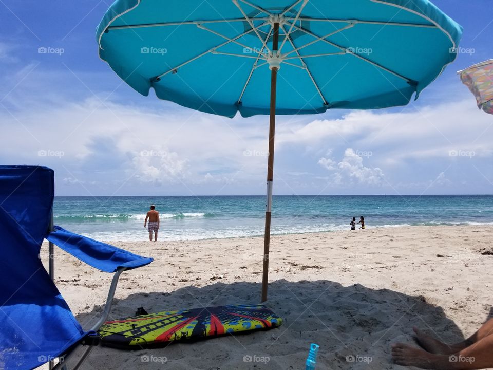 At the beach under a blue umbrella