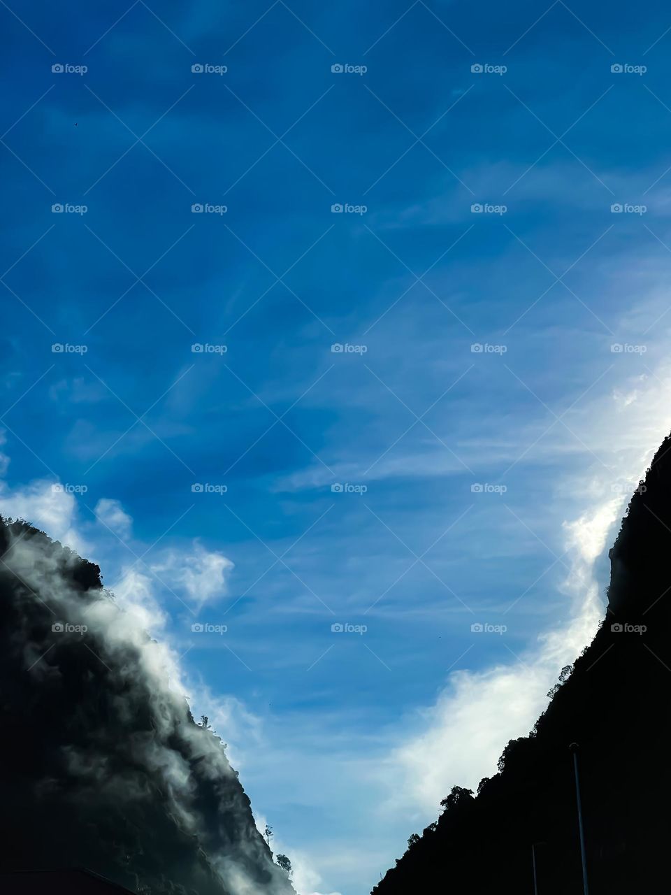 Fog surrounded the two hills with blue sky as a background 