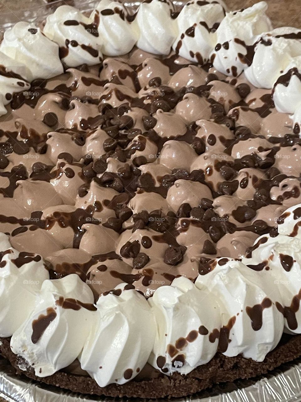 A photo of a chocolate pie with whipped cream and chocolate chips on top. 