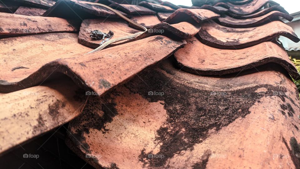 View of old school roof tiles made of clay on the roof of a house with a rickety bamboo frame, clay tiles that are generally installed on houses in Indonesia.
