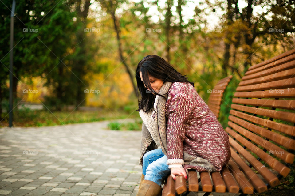 Young beautiful woman sitting on bench in park