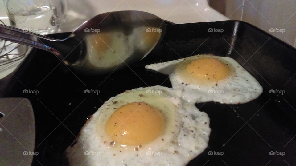 Frying eggs reflecting in the spoon