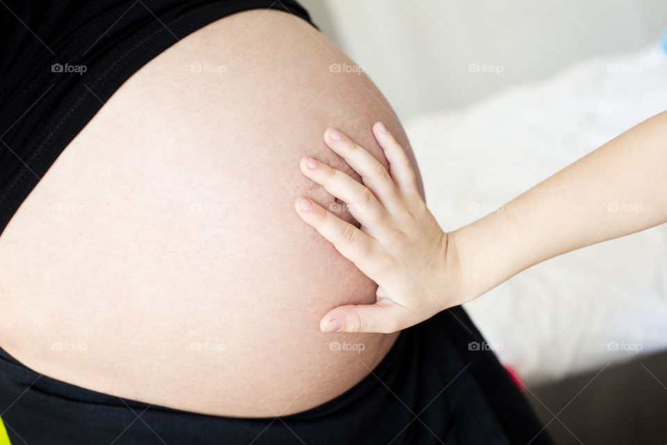 Child touching the pregnant mother's belly