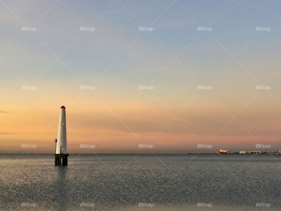 View of lighthouse in sea during sunset