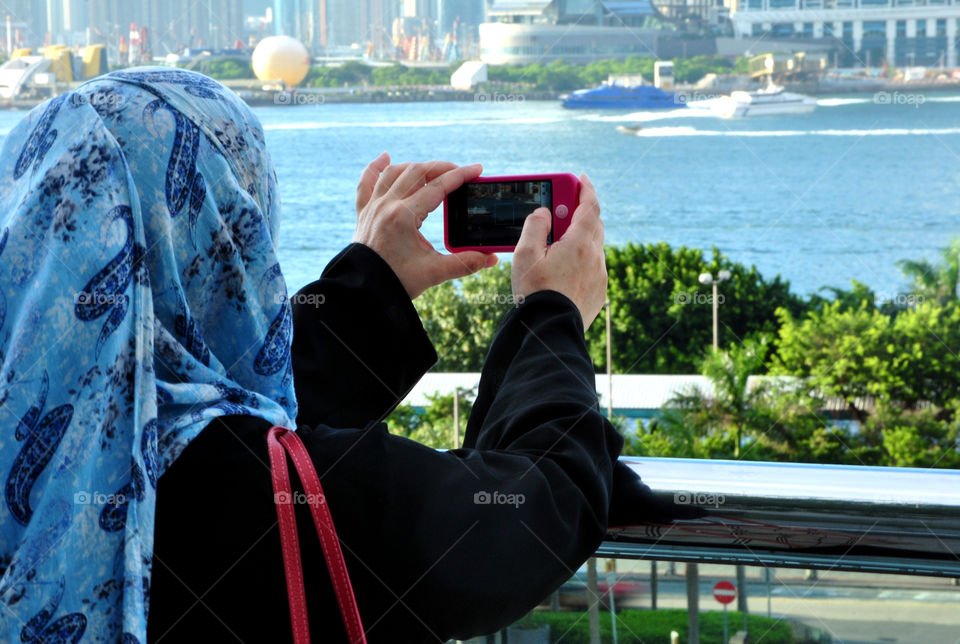 Lady taking a photo of the city with a  mobile phone