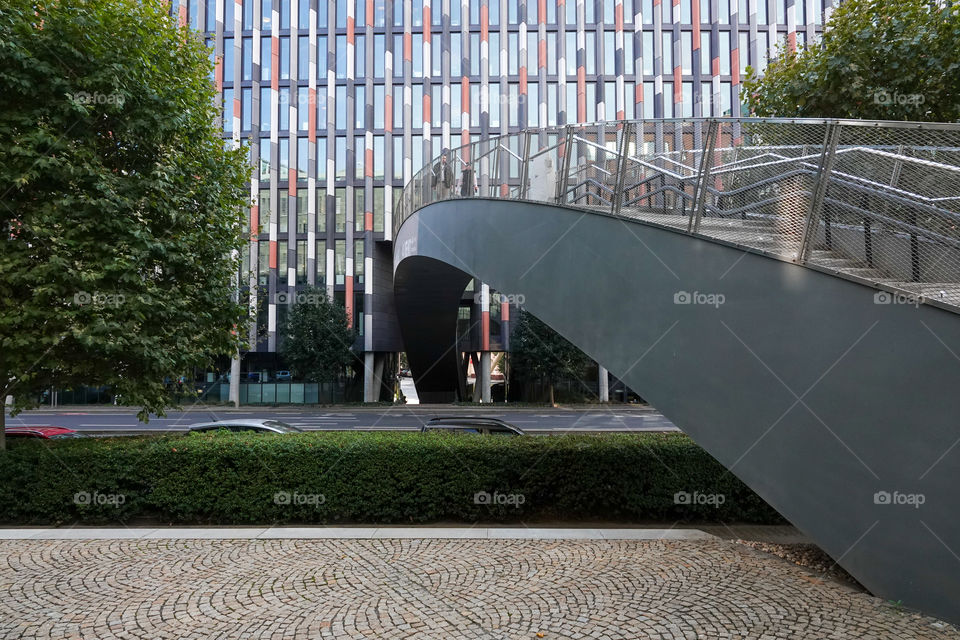 A bridge over a road and then passing through an office building.