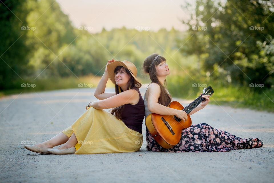 Young beautiful bohemian style women with guitar on the road