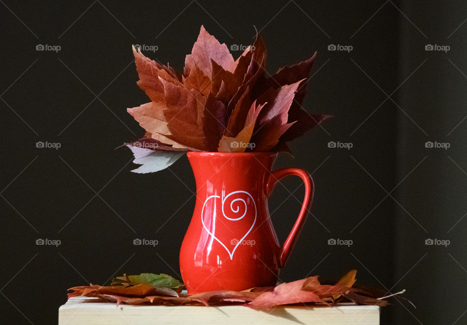 Red autumn leaves in a red vase