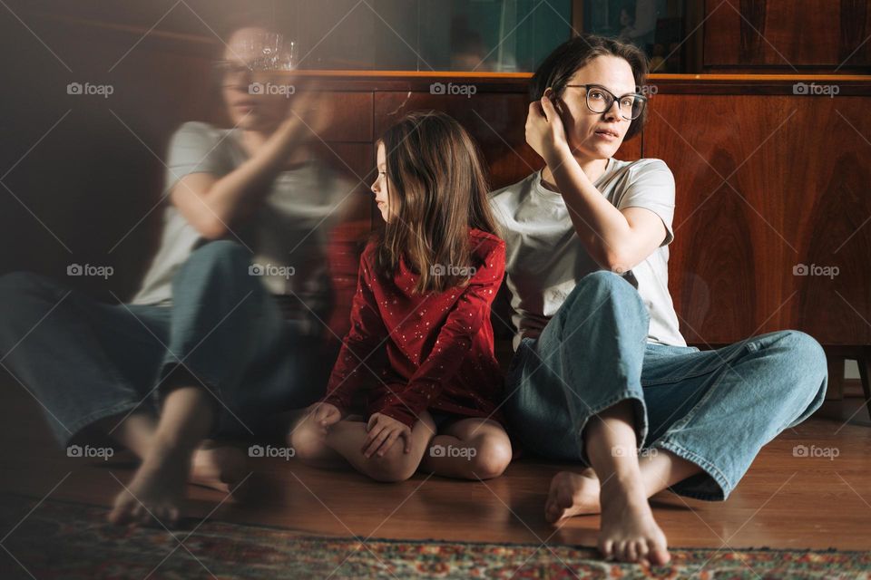 Tween girl and her mother sitting on the floor in living room at home
