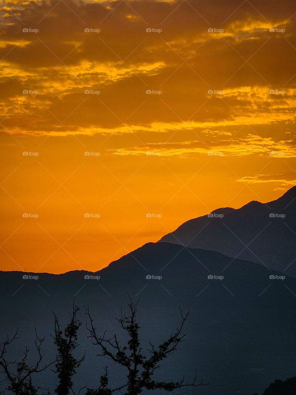 Orange skies, sunset in Montenegro with the black mountains in the background, creating a dark mode nightfall.