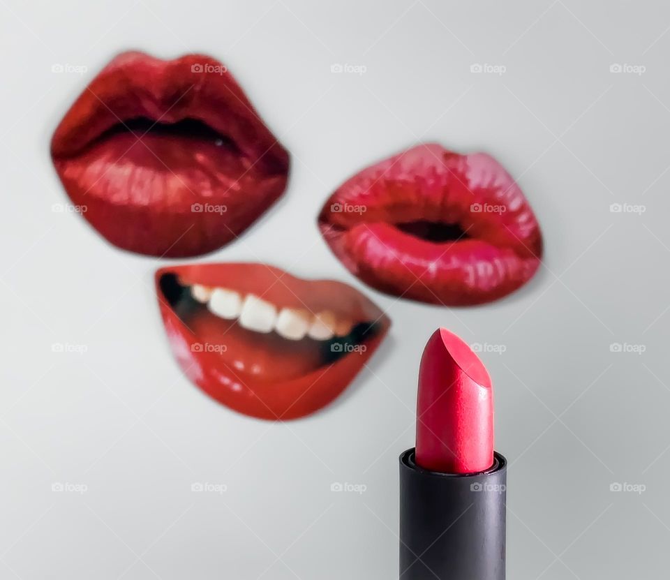 Red lipstick displayed in front of cut out lip shapes stuck to a white background (PLS NOTE - Not a graphic, cut outs used from ‘selfie party kit’ and stuck to white background on which lipstick was photographed against)