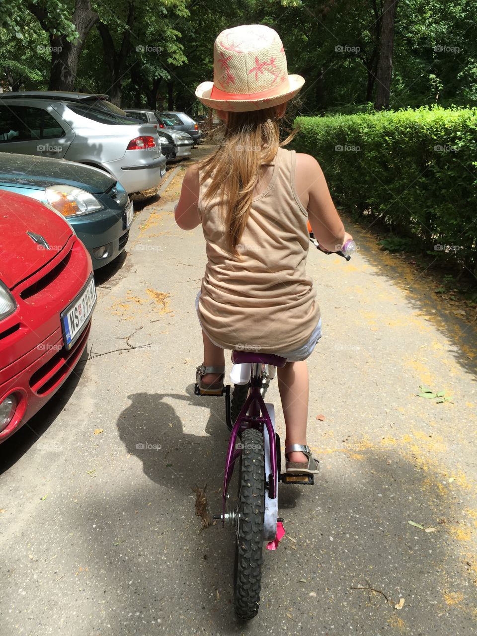 Little girl wearing hat on a hot summer day riding a bike