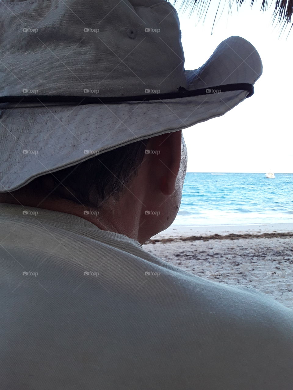 man with hat looking at the ocean