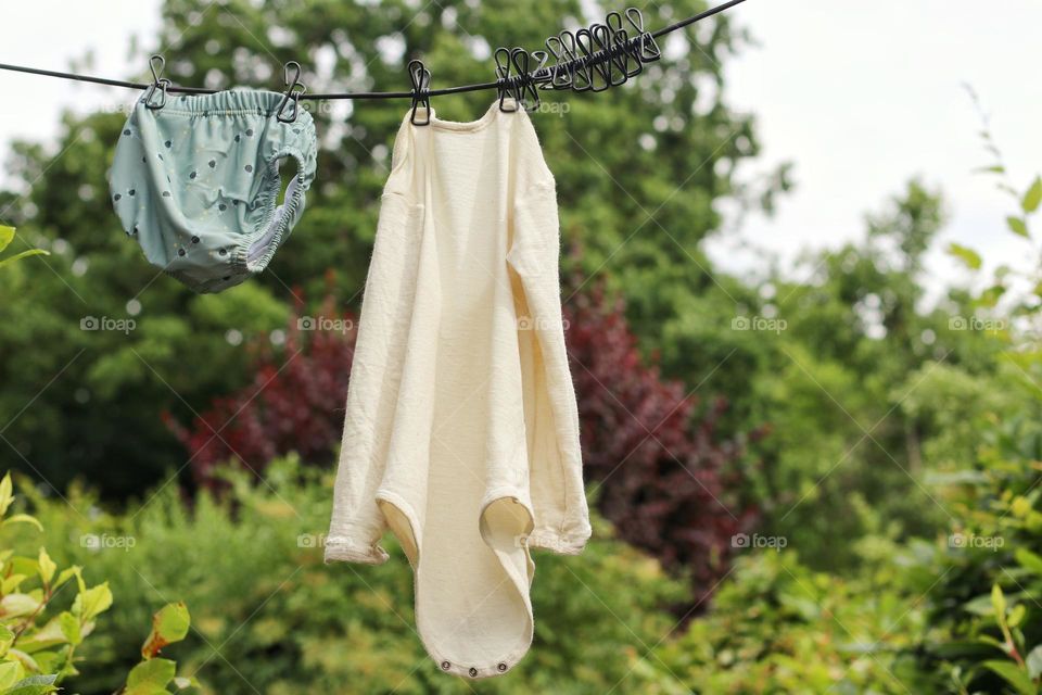 Baby clothes hang on a clothesline to dry in the garden