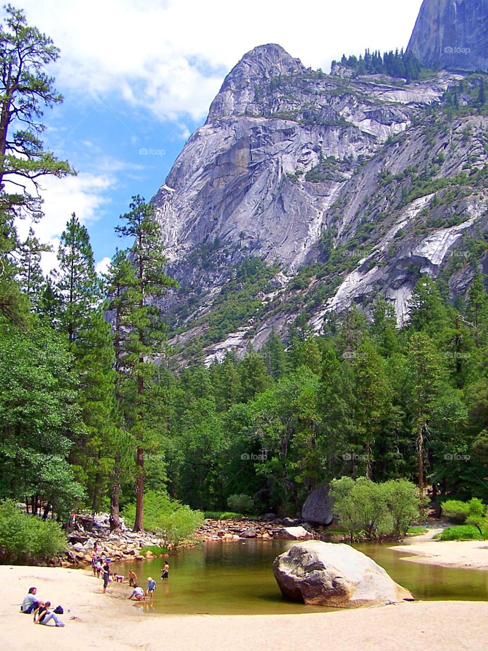 Swimming hole in Yosemite valley. Swimmers seem tiny against the backdrop of the mountains. 