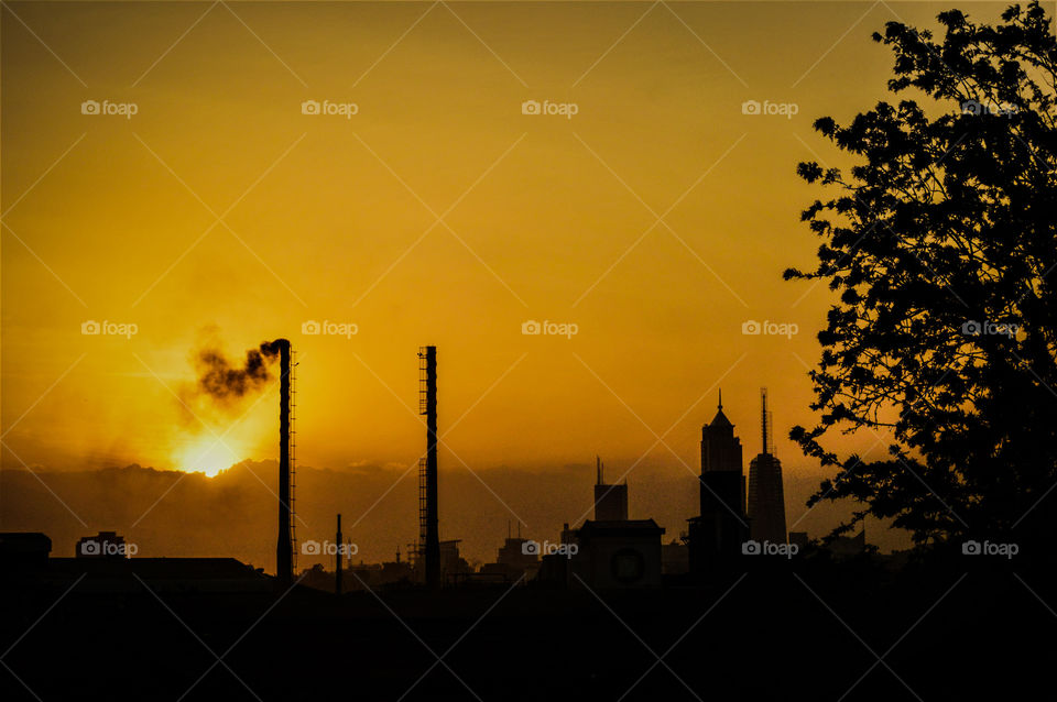 Nairobi cityscape behind a factory chimney bellowing smoke on a golden evening sunset