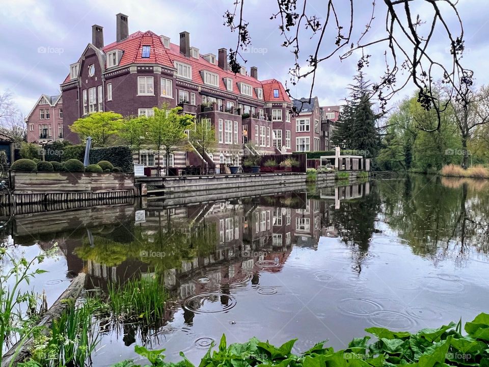 Urban nature: side view of the beautiful town house on the city public park pond channel with reflection in the smooth water surface 