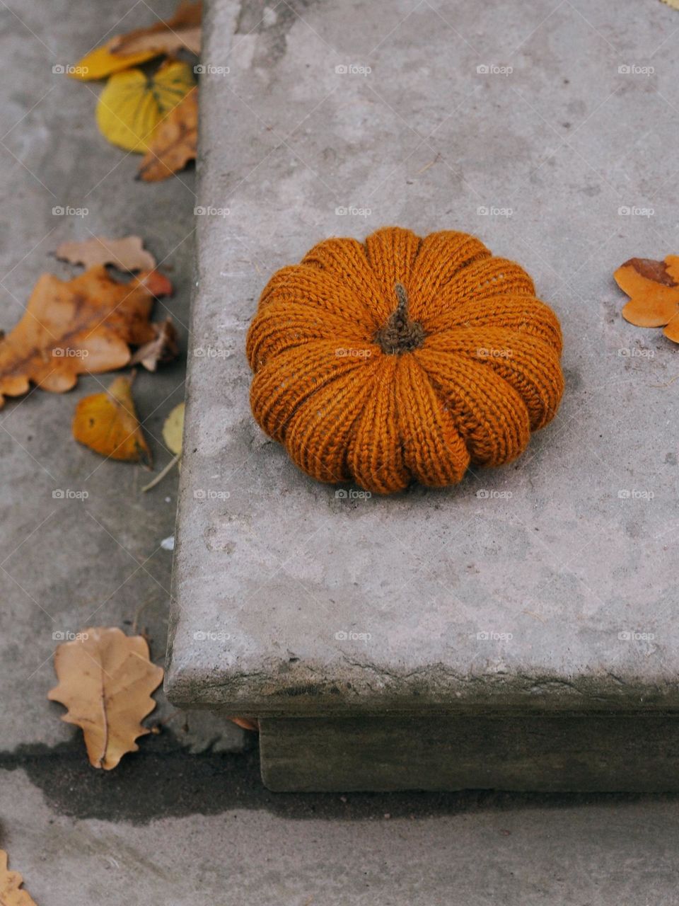 Handmade knitted Halloween pumpkin on a brick stair in autumn day, nobody 