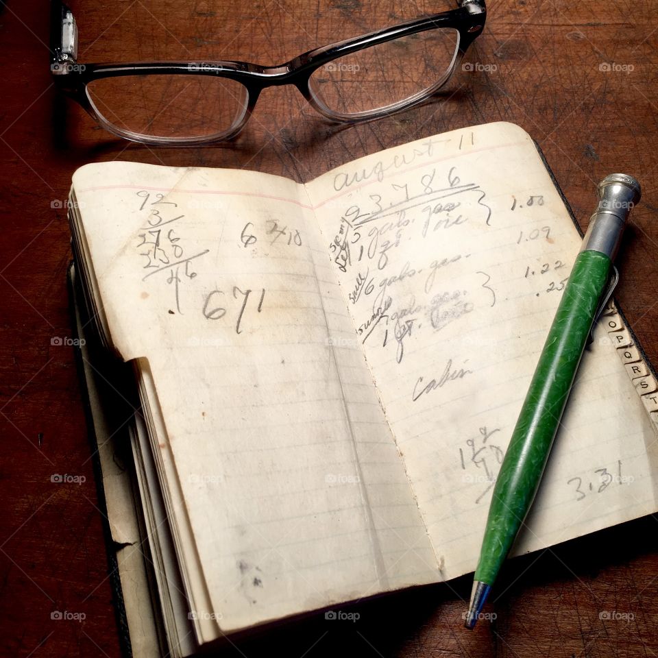Vintage notebook and mechanical pencil with spectacles on wood desk.