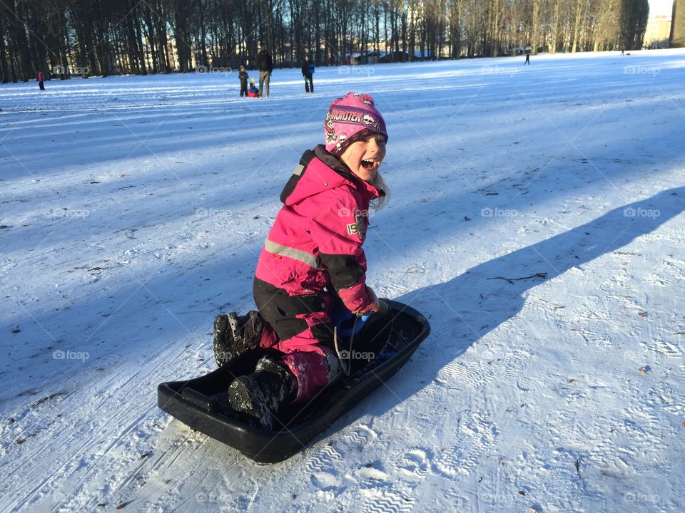 Young girl is riding her sledge in the winter.