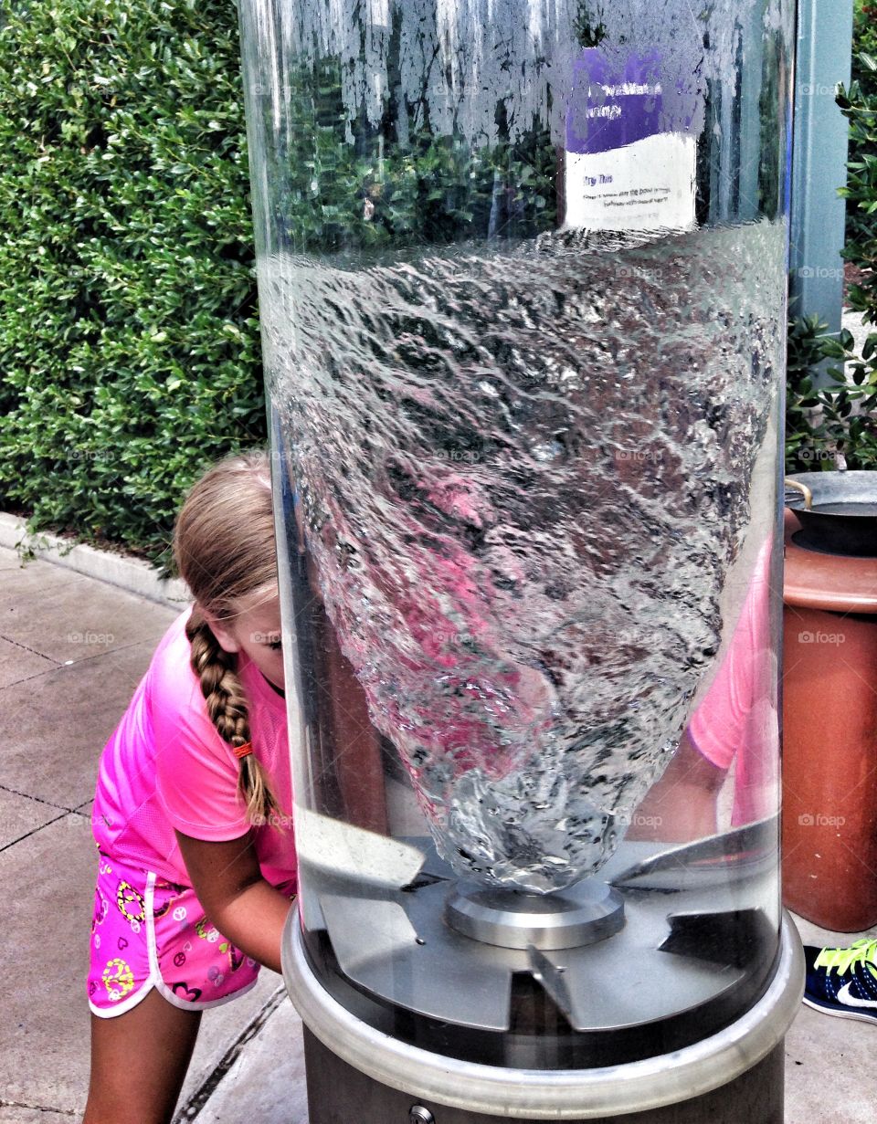 Twisted experiment. Girl making a water funnel at an outside exhibit