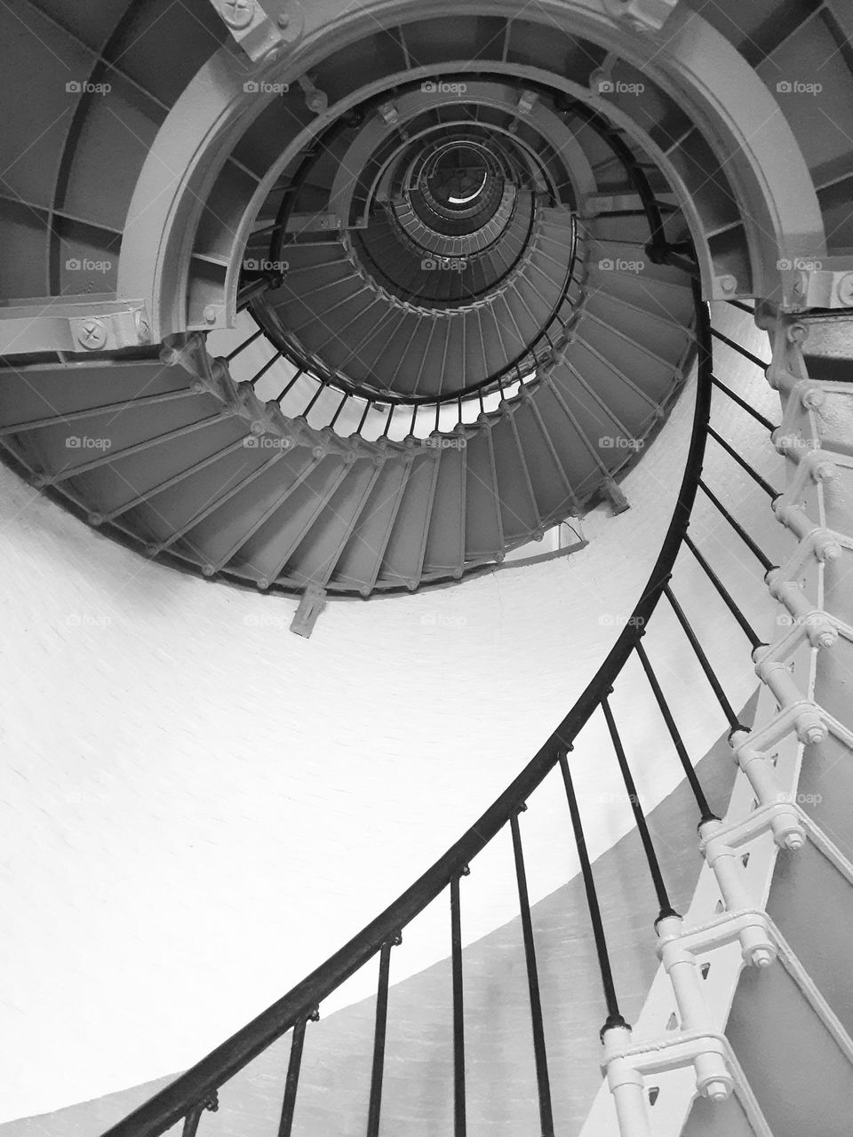 A black and white photo of the steep spiral staircase of the Ponce Inlet Lighthouse.