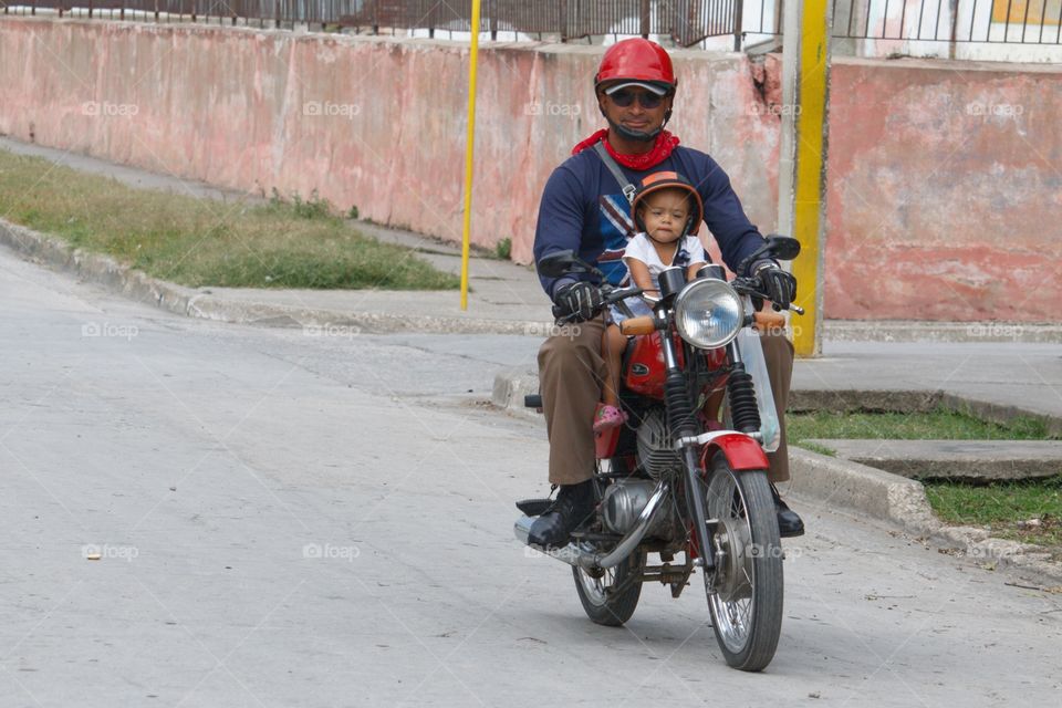 Father riding motor bike with his daughter wearing helmet