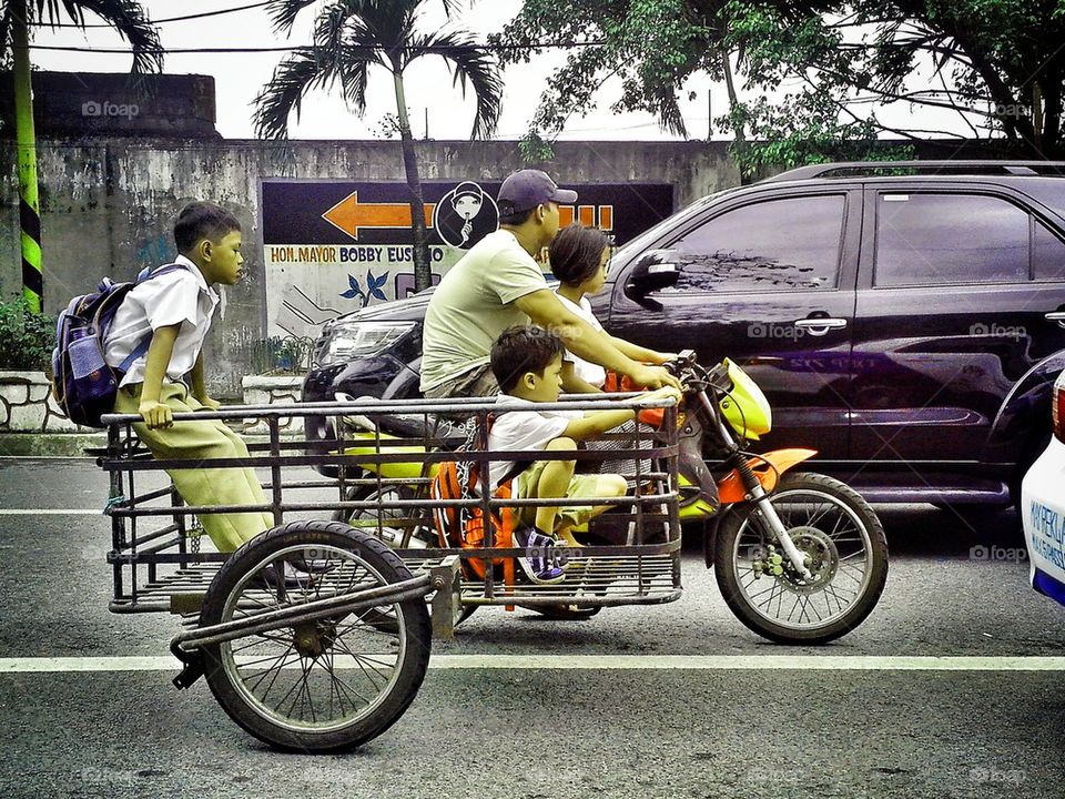 asian students riding a tricycle to get home