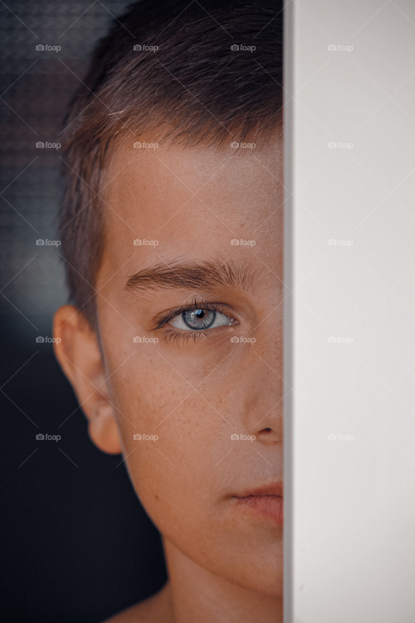 Close-up portrait of young boy looking through window frame