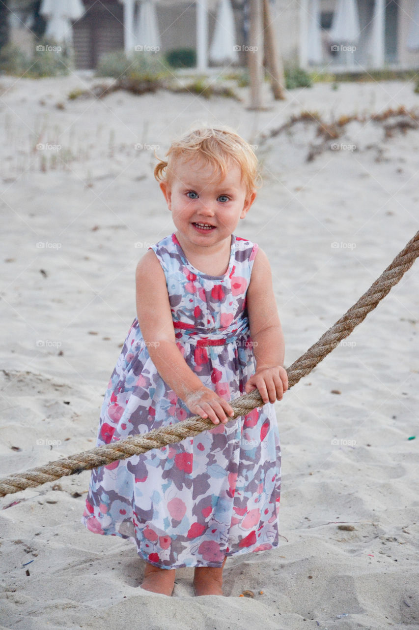 Adorable young girl of the age of 18 month. Posing for a picture on the beach of Majorca Spain. The girl is from Sweden.