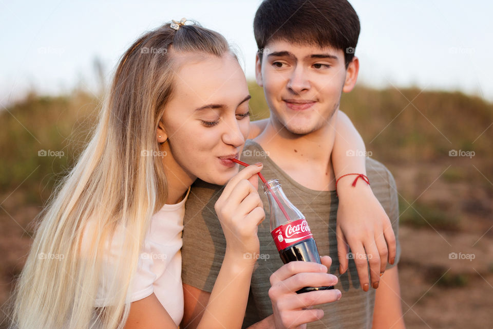 Boy looking at girl drinking cold drink